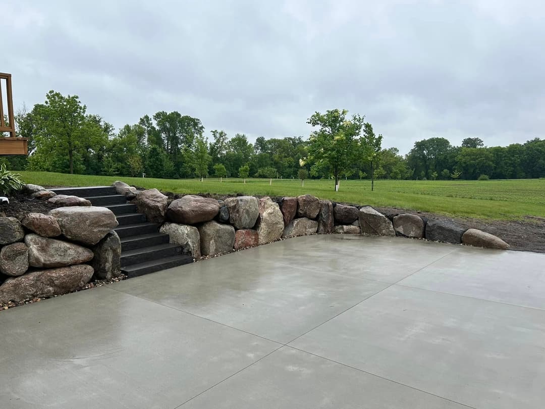 Stone steps leading up to a landscaped area with lush greenery and overcast skies.