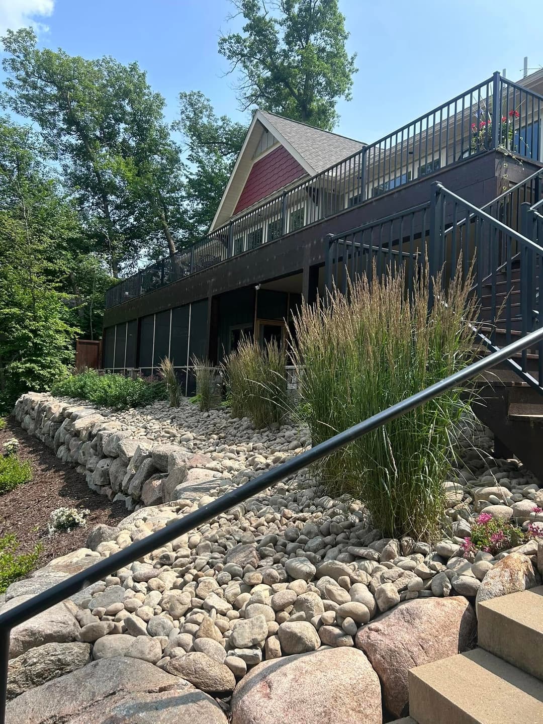 Modern home with a stone pathway, surrounded by lush greenery and decorative grasses.