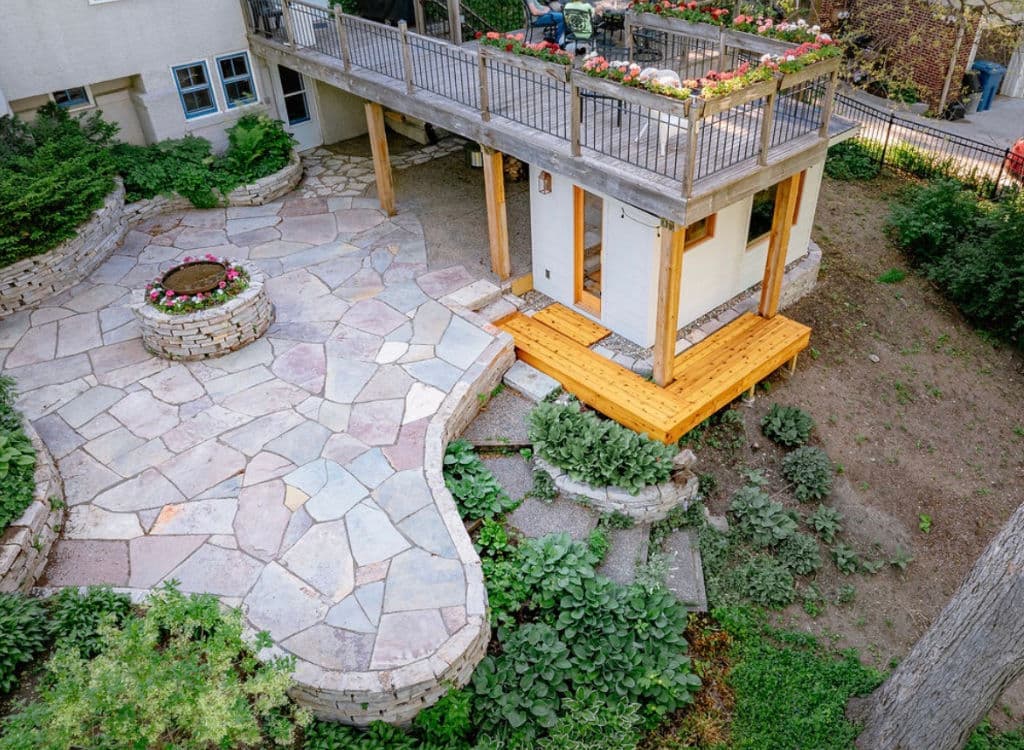 Stunning landscaped patio with stone path, wooden deck, and vibrant flower planters.